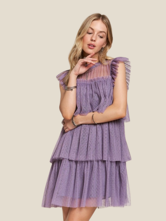 Woman wearing a purple tiered dress on a beige background